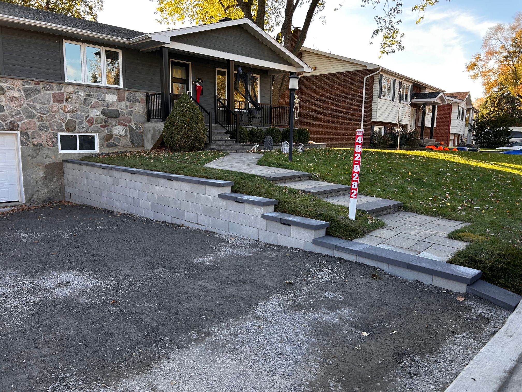 Muret en brique avec entrée de maison en pavé uni gris à Brossard, après les travaux effectués par Paysagement et excavation Campex.